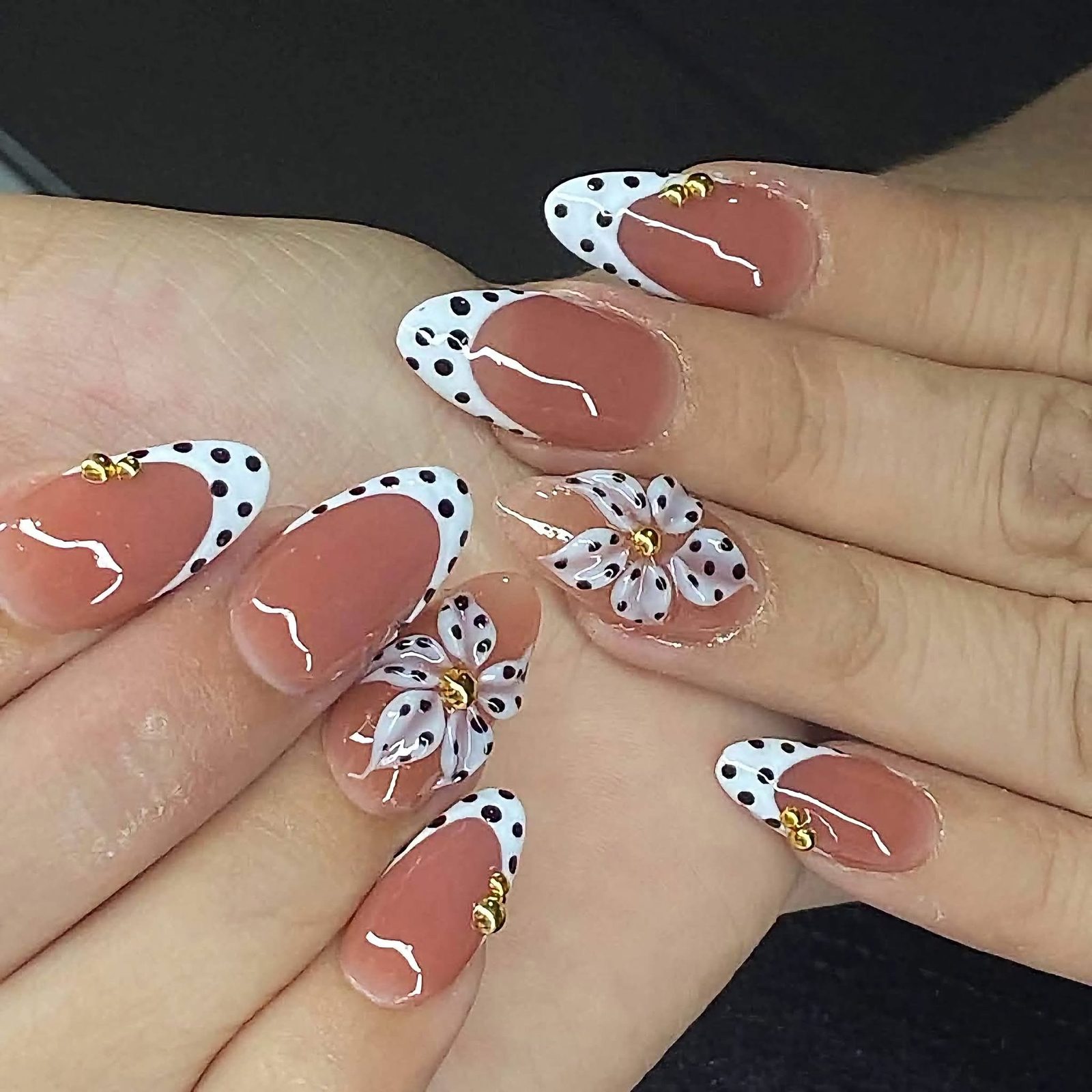White French tips with black polka dots, a 3D white flower and gold studs