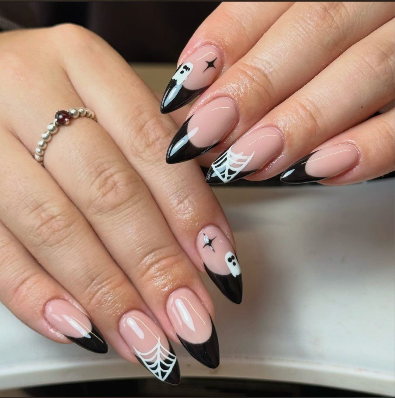 Stiletto nails with black French tips, a web and a ghost
