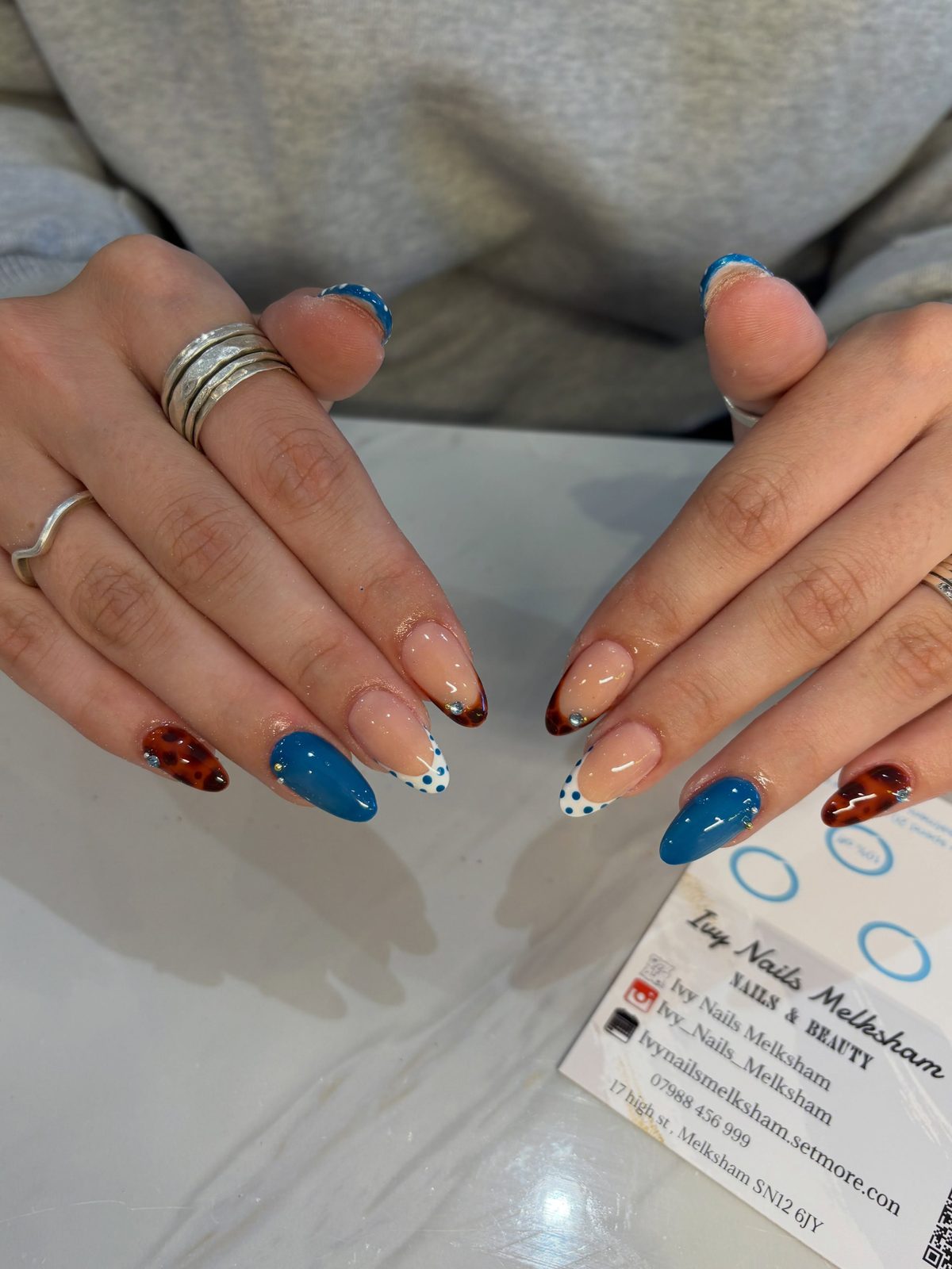 Short almond nails with teal, red tortoiseshell and polka-dot accents