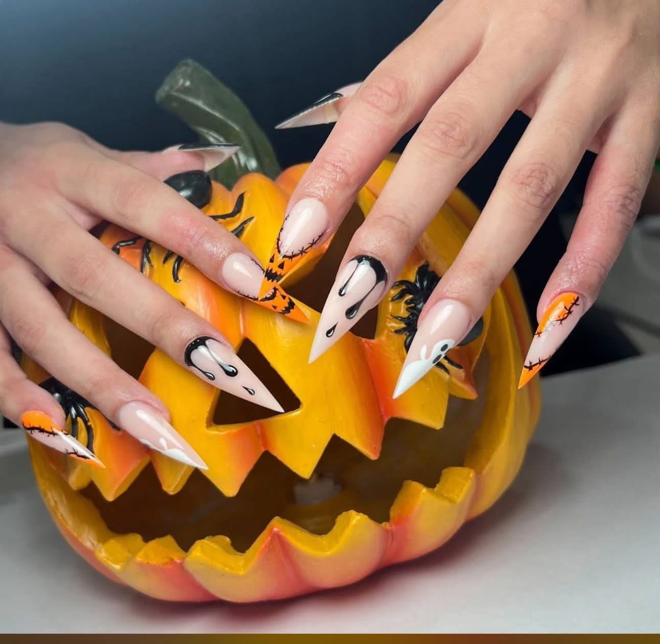 Long stiletto Halloween nails held over a carved pumpkin
